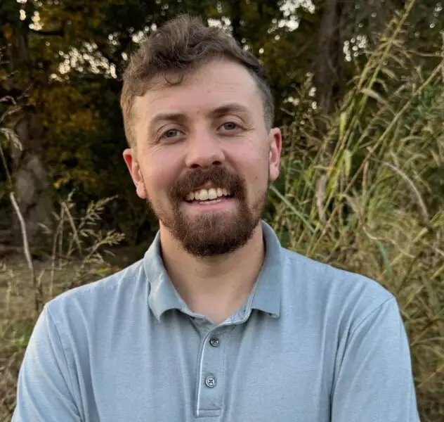 Professional photo of counselor JD McDonald shown from chest up looking at camera and smiling while wearing a collared button up shirt.